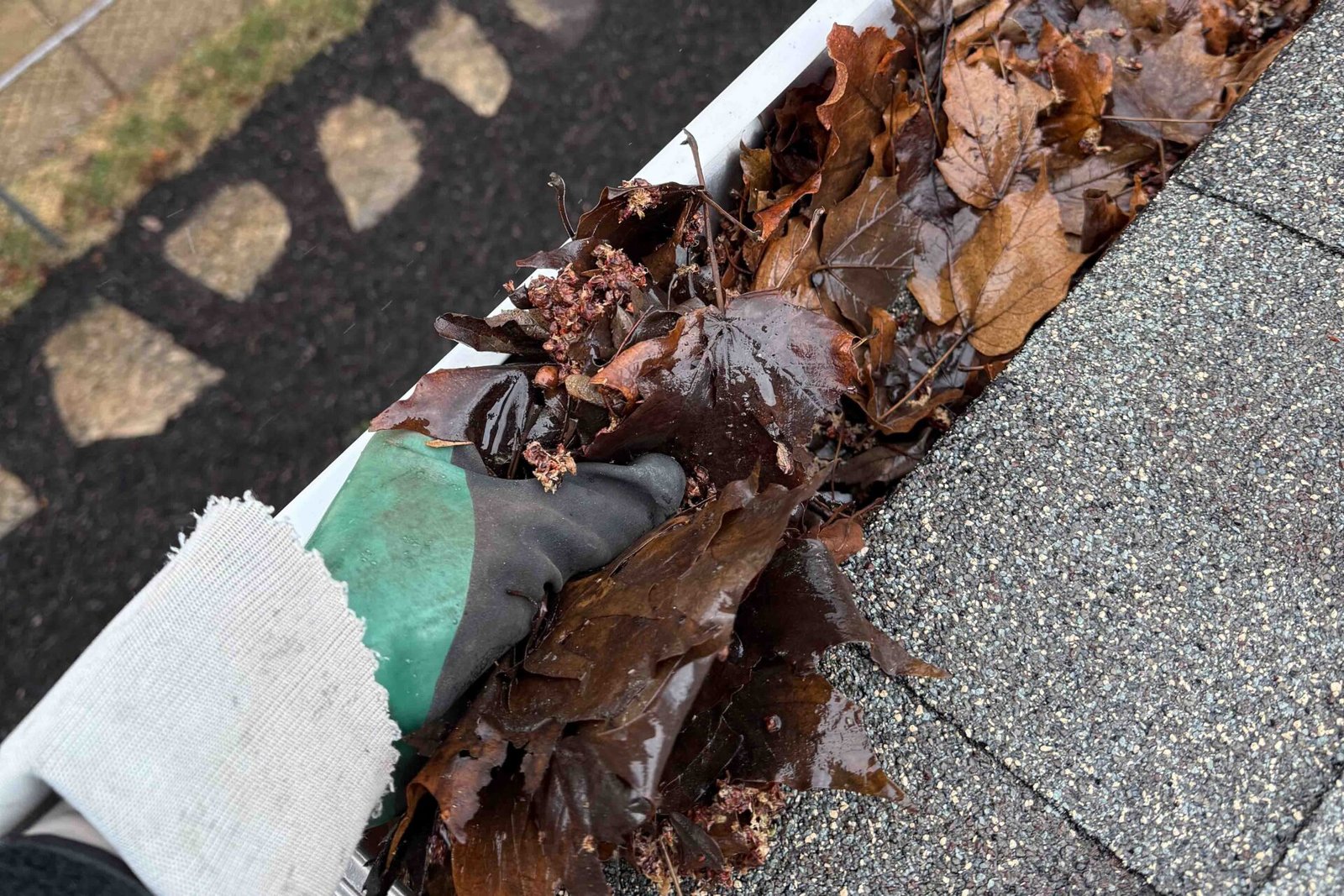 Lifted gutter guard revealing leaves and small debris inside a Naperville home’s gutter